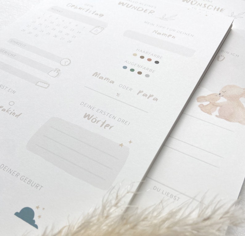 May include: A printable baby memory book with a light blue and white color scheme. The cover features a watercolor illustration of two bunnies hugging. The book includes sections for recording the baby's birthdate, time, weight, length, first words, and other milestones.