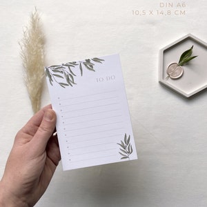May include: A white to-do list notepad with a green leafy design and the words "TO DO" printed in pink. The notepad is DIN A6 size, which is 10.5 x 14.8 cm.