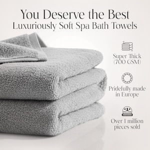 May include: A stack of three light gray spa bath towels. The towels are thick and soft, with the text "You Deserve the Best Luxuriously Soft Spa Bath Towels". The image also states the towels are super thick (700 GSM) and made in Europe.