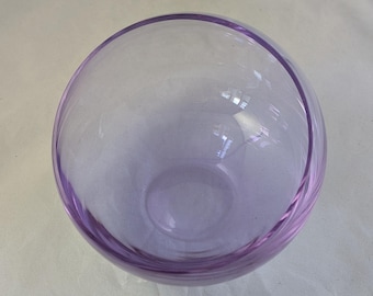 May include: A clear glass bowl with a light purple hue. The bowl has a rounded shape and a smooth, glossy finish.