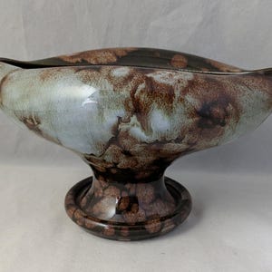 May include: A ceramic bowl with a brown and white marbled glaze. The bowl is on a pedestal with a matching glaze.