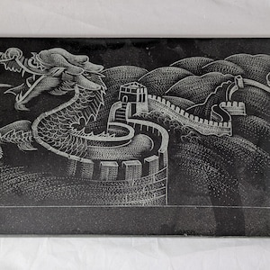 May include: Black and white engraved stone plaque depicting a dragon flying over the Great Wall of China. The dragon is detailed with scales and has a long tail. The wall is shown with towers and a winding path.