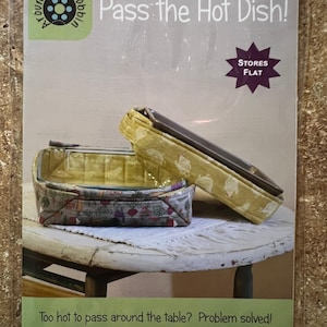 May include: A package for a sewing project titled "Pass the Hot Dish!" features two fabric hot dish carriers. The carriers are in a variety of colors and patterns. The package states the baskets are for 9 x 9 and 9 x 13 inch pans.