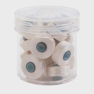 May include: A clear plastic cylindrical container filled with multiple small spools of white thread. Each spool features a central core with a light blue inner ring. The container has a matching transparent screw-on lid that seals the contents inside.