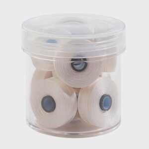 May include: A clear plastic cylindrical container filled with multiple small spools of off-white thread. Each spool features a light blue circular center core. The container has a matching transparent lid that fits securely over the top opening.