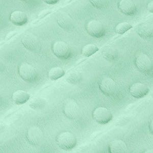 Op de afbeelding: Close-up van een zachte, mintgroene stof met een getextureerd, kuiltjespatroon. De stof heeft een pluche, fluwelen uitstraling, met verhoogde, afgeronde stippen gelijkmatig verdeeld over het oppervlak. Het algehele effect is er een van comfort en tactiele aantrekkingskracht.