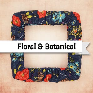 May include: A navy blue floral and botanical patterned fabric with red, yellow, and blue flowers. The fabric is shaped in a square with the words "Floral & Botanical" in a white banner across the center.