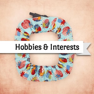 May include: A light blue, circular cover with a colorful pattern of red, blue, and yellow shapes. The cover has a black handle at the top and the text "Hobbies & Interests" on a white banner.