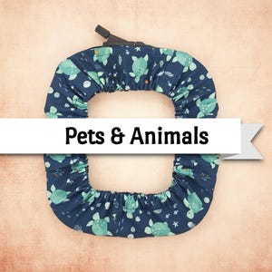 May include: A navy blue pet carrier cover with a pattern of light green turtles and white stars. The cover has a black handle and the text "Pets & Animals" on a white banner.