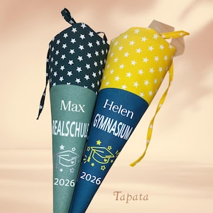Könnte beinhalten: Zwei Schultüten, eine teal-farbene und eine gelbe, mit weißen Sternmustern. Auf der teal-farbenen Tüte stehen die Namen "Max" und "Realschule", sowie das Jahr "2026". Auf der gelben Tüte stehen "Helen" und "Gymnasium", ebenfalls mit "2026".