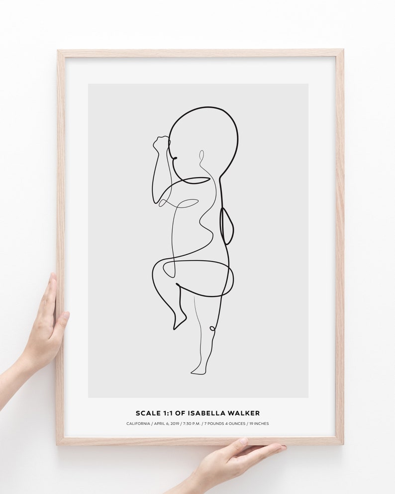 May include: A black and white line drawing of a baby in a minimalist style. The drawing is framed in a light wood frame. The text below the drawing reads "SCALE 1:1 OF ISABELLA WALKER CALIFORNIA/APRIL 6, 2019/7:30 P.M./7 POUNDS 4 OUNCES/19 INCHES"