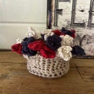 May include: A small crocheted basket filled with red, white, and blue crocheted flowers.