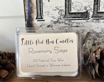 Op de afbeelding: Een witte was smelt in een doorzichtige plastic container met een rood hart en de tekst "Little Red Hen Candles Rosemary Sage All Natural Soy Wax Hand Poured in Winona, Indiana"