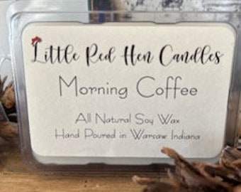 May include: A small, clear container of soy wax candle with a white label that reads "Little Red Hen Candles Morning Coffee All Natural Soy Wax Hand Poured in Warsaw Indiana."