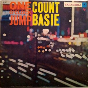 May include: A vintage vinyl record cover featuring a blurred city lights background. The album title is "One O'Clock Jump" by Count Basie and the Columbia Records label is visible in the top right corner.