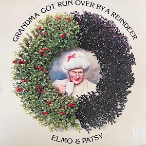 May include: A Christmas album cover featuring a wreath made of green and black foliage with a woman in a white hat and glasses holding a cup of coffee. The text on the cover reads "Grandma Got Run Over By A Reindeer" and "Elmo & Patsy".
