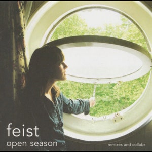 May include: A woman looks out a round window with a white frame. The window is open and the top half is tilted up. The woman is wearing a dark blue shirt and has dark hair. The text "feist open season remixes and collabs" is at the bottom of the image.