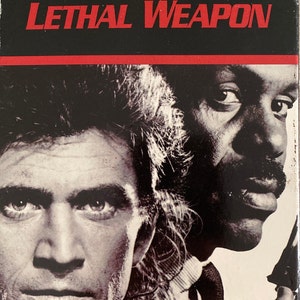 May include: A VHS tape cover for the movie Lethal Weapon, featuring Mel Gibson and Danny Glover. The cover is black with red text and a photo of the two actors.