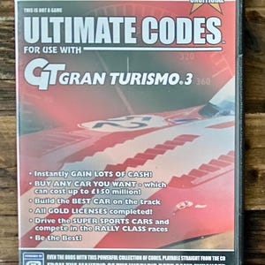 May include: A PlayStation 2 game case for "Ultimate Codes" for use with Gran Turismo 3. The cover features a red and white race car graphic. Text includes "100% Unofficial" and various game enhancement features.