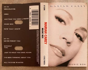 May include: A Mariah Carey "Music Box" cassette tape. The cover features a close-up of Mariah Carey's face. The cassette case lists song titles like "Dreamlover" and "Hero". The Columbia Records logo is visible.
