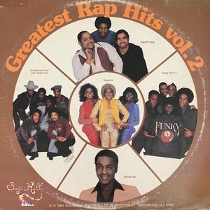 May include: A vintage vinyl record album cover titled "Greatest Rap Hits vol. 2." The cover features a brown and white design with multiple images of rap groups, including Sugarhill Gang and Funky Four + 1. The album was released in 1981.