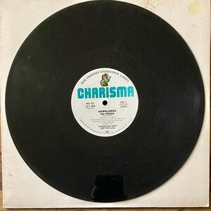 May include: A black vinyl record with a white and teal label featuring the text "CHARISMA" and "HAWKLORDS PSI POWER." The record is on a white paper sleeve. The label also includes the text "PROMOTION COPY NOT FOR SALE."