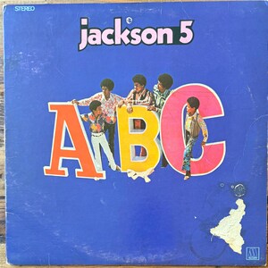 May include: A vintage vinyl record cover for the Jackson 5 album titled ABC. The blue cover features the text jackson 5 at the top and large, colorful letters A, B, and C. Five individuals are depicted interacting with the letters.