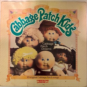 May include: Vintage Cabbage Patch Kids album cover featuring five dolls with different hair colors and styles. The album title, "Cabbage Patch Dreams," is displayed above the dolls. The cover also includes the text "10 original Cabbage Patch songs."