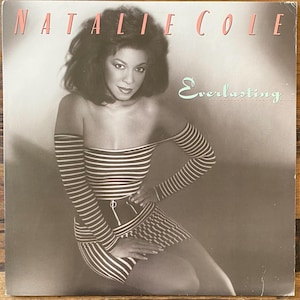 May include: Album cover for Natalie Cole's "Everlasting." The album art features a woman in a striped off-the-shoulder top and skirt. The album title is in a cursive font, and the artist's name is in a bold, pink font.