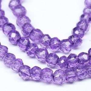 May include: A strand of purple amethyst beads, each bead is faceted and has a slightly irregular shape. The beads are strung on a clear thread and are ready for jewelry making.
