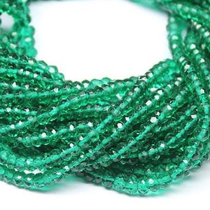 May include: A strand of emerald green faceted glass beads. The beads are small and round, and they are strung together on a clear thread.