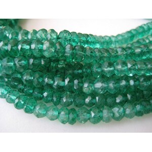 May include: A strand of faceted green gemstone beads. The beads are small and have a slightly irregular shape. The beads are strung on a clear thread.
