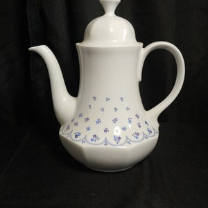 May include: White ceramic coffee pot with a blue and purple floral pattern. The pot has a lid and a handle.