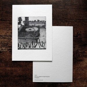 May include: A monochrome print depicting a pottery studio, with a potter's wheel and various tools. The print is on a white card, accompanied by a blank card. Text at the bottom reads "Studio" and "The Galeria Bosch".