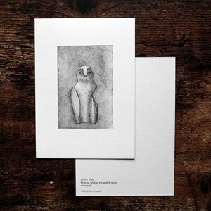 May include: A monochrome print of an owl-like form on white paper, mounted on a larger white card, with a blank card beneath. The text "Orion Wing" and other text is visible on the bottom right of the card.