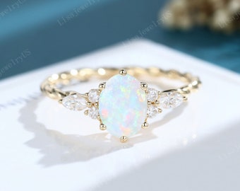 May include: A gold ring with a white opal gemstone surrounded by smaller diamonds. The ring has a twisted band.