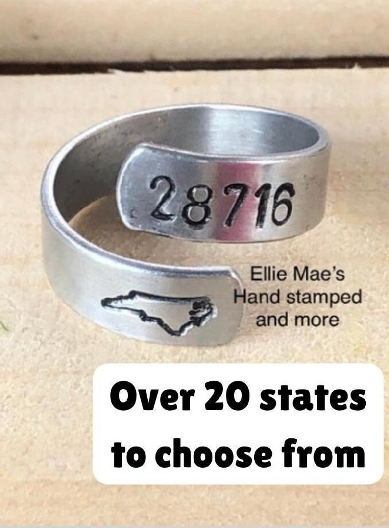 May include: A silver ring with the state of North Carolina and the numbers 28716 engraved on it. The ring is made by Ellie Mae's Hand Stamped and more. The text "Over 20 states to choose from" is also visible in the image.