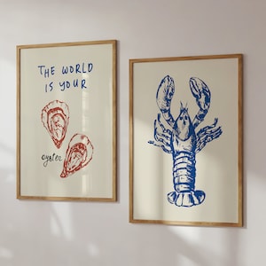 Peut inclure: Deux impressions encadr&eacute;es sur le th&egrave;me nautique. L'impression de gauche repr&eacute;sente une illustration rouge et blanche de deux hu&icirc;tres avec le texte "Le monde est votre hu&icirc;tre". L'impression de droite repr&eacute;sente une illustration bleue d'un homard.