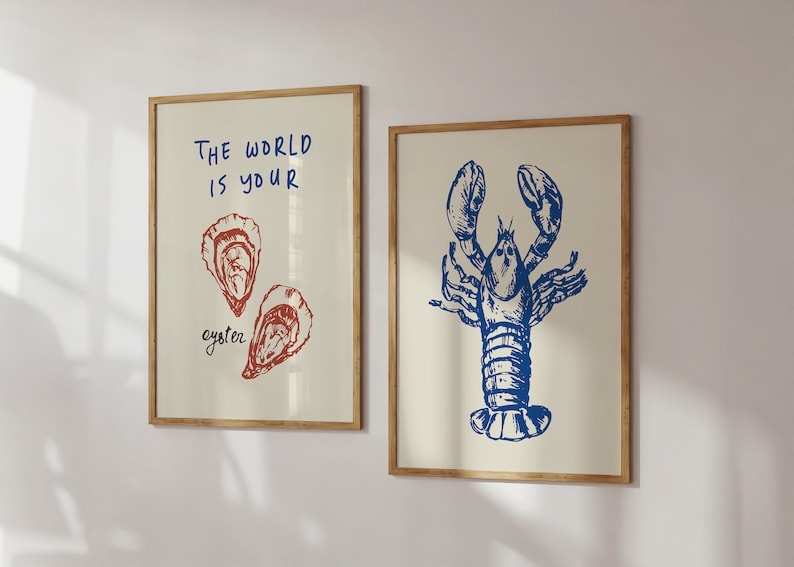 Peut inclure: Deux impressions encadr&eacute;es sur le th&egrave;me nautique. L'impression de gauche repr&eacute;sente une illustration rouge et blanche de deux hu&icirc;tres avec le texte "Le monde est votre hu&icirc;tre". L'impression de droite repr&eacute;sente une illustration bleue d'un homard.