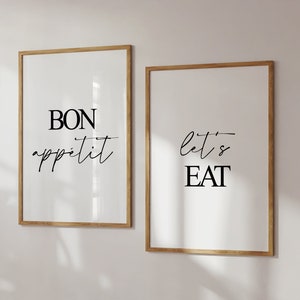 May include: Two framed prints with black text on a white background. The left print says "BON appetit" and the right print says "let's EAT".