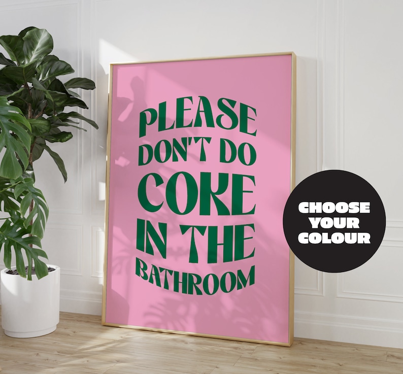 May include: A pink poster with the text "PLEASE DON'T DO CORE IN THE BATHROOM" in green letters. The poster is framed in gold and has a black circle with the text "CHOOSE YOUR COLOUR" in white letters.