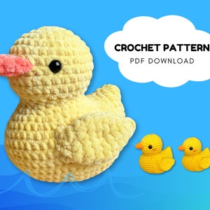 May include: Crochet pattern PDF download for a yellow crocheted duck. The duck has a pink beak and black eyes. There are two smaller yellow crocheted ducks in the background.