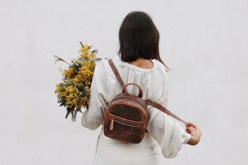 A woman wearing a brown leather mini backpack