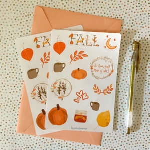 May include: A sheet of stickers with a fall theme. The stickers feature illustrations of pumpkins, leaves, coffee cups, trees, and a crescent moon. The text "FALL" and "I love fall most of all!" are also included on the sheet.