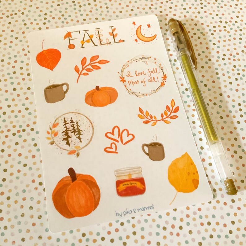 May include: A sheet of fall-themed stickers with illustrations of pumpkins, leaves, coffee mugs, a moon, a forest, hearts, and a jar of apple sauce. The stickers are on a white background and have the text "FALL" and "I love fall most of all!" The sheet is signed "by pika & mammot".