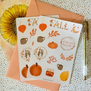 May include: A sheet of fall-themed stickers with illustrations of pumpkins, leaves, coffee cups, a moon, and the words "Fall" and "I love fall most of all!" The stickers are on a white background and have a hand-drawn style.
