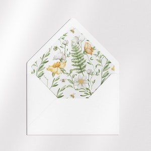 May include: A white envelope with a floral pattern on the inside flap. The pattern features yellow and white flowers, green leaves, and small bees.
