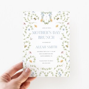 Pu&ograve; includere: Un invito bianco con un design floreale con farfalle, api e fiori. Il testo recita "Unisciti a noi per un brunch della Festa della Mamma in onore di Aleah Smith. Sabato 23 maggio alle 11:30, 404S Celebration Way, Santa Barbara, CA. Per favore, conferma la tua presenza a Emily al 805.555.5555"