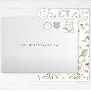 May include: A white envelope with a floral pattern on the back. The envelope has a "Paperless Post" stamp and a monogrammed stamp with the letter "A". The text "YOUR RECIPIENT'S NAME HERE" is printed on the front of the envelope.