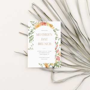 以下が含まれることがあります： 花柄の縁取りが施された白い招待状で、"JOIN US FOR MOTHER'S DAY BRUNCH"という文字が桃色のオレンジ色で書かれています。招待状には、11月23日土曜日午前11時にサンタバーバラの4001 Celebration Wayで行われるブランチのイベントの詳細が記載されています。RSVP用の電話番号も記載されています。